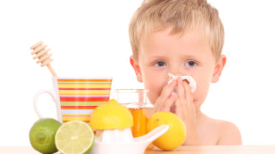3-4 years old boy with cold and flu remedy on white /focus on kid/
